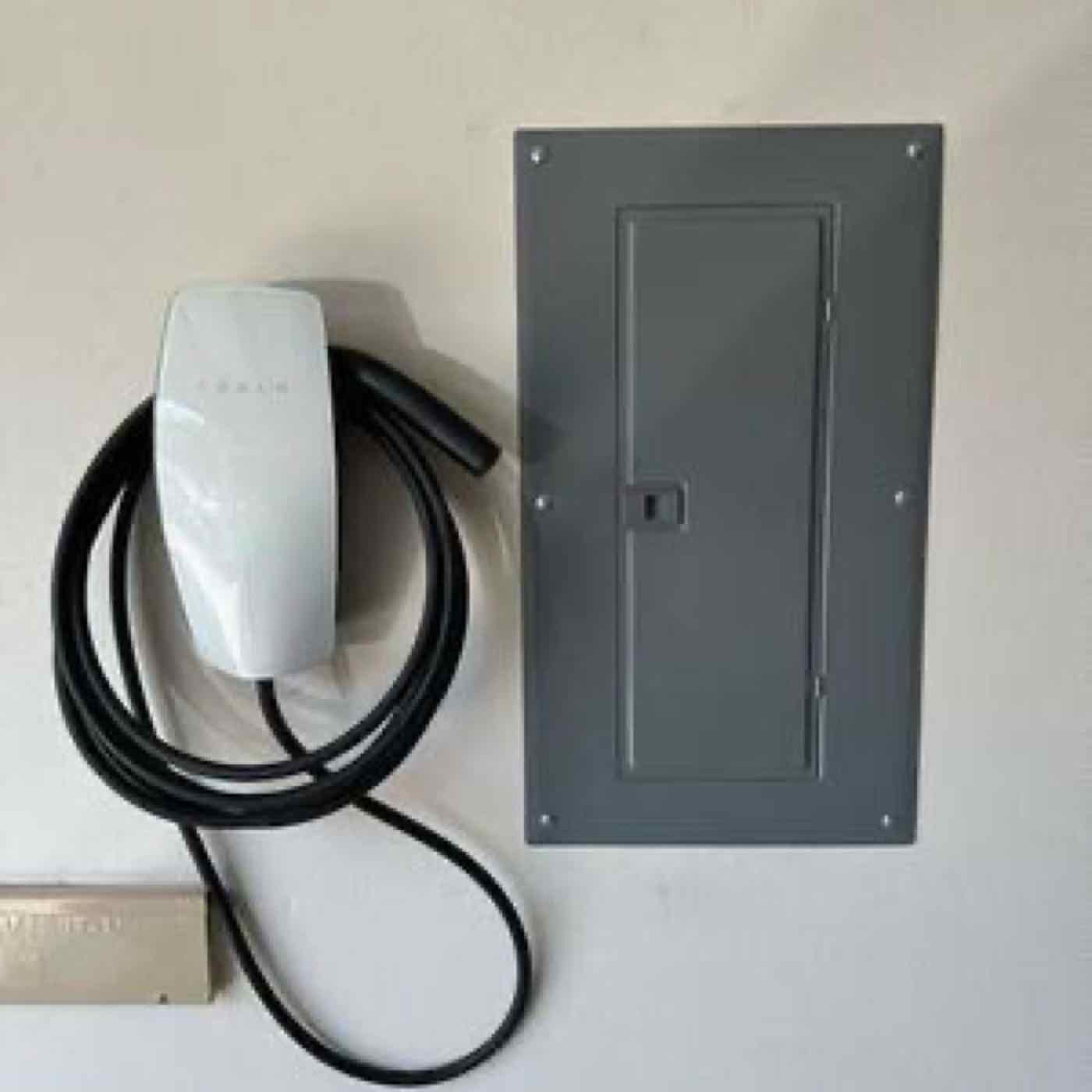 An EV charger installed beside an electrical panel.